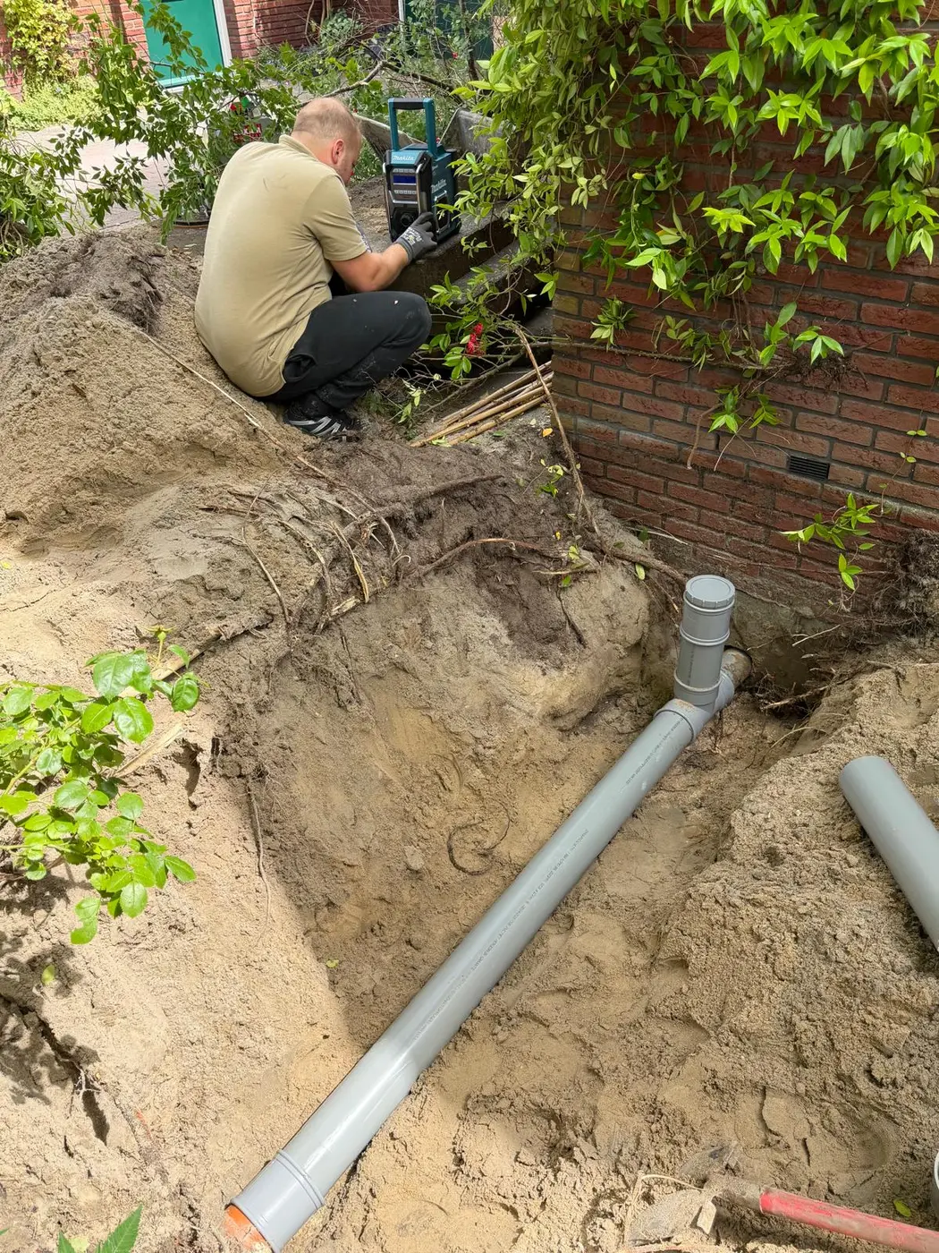 Monteur werkt naast een opengelegde nieuwe PVC-rioolleiding